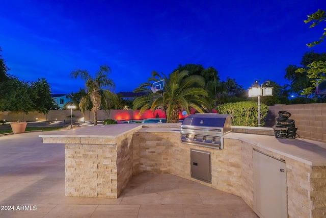 patio at night with area for grilling and exterior kitchen