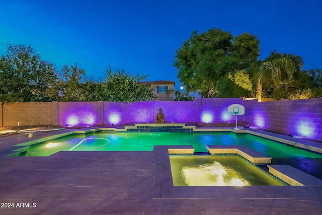 pool at twilight featuring pool water feature