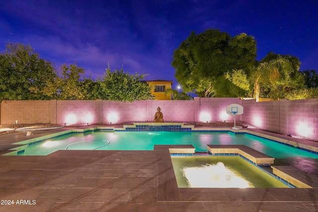 pool at night with an in ground hot tub and pool water feature