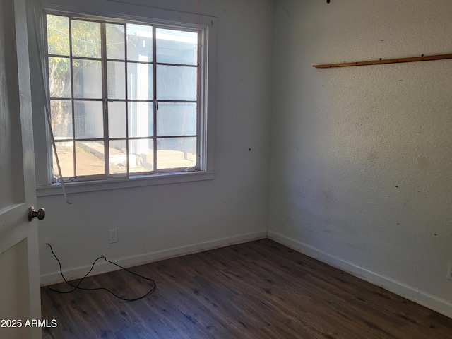 empty room featuring plenty of natural light, wood finished floors, and baseboards