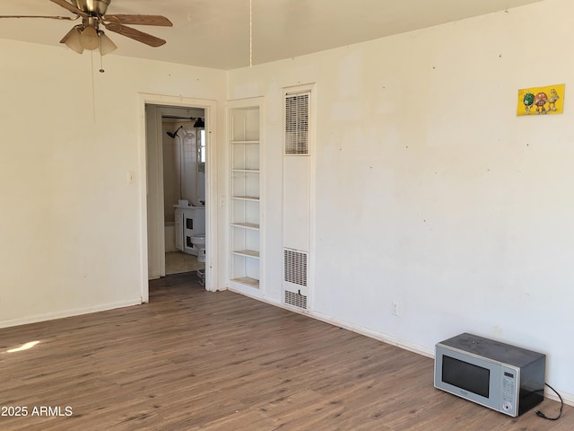 unfurnished room with a ceiling fan, visible vents, wood finished floors, and baseboards