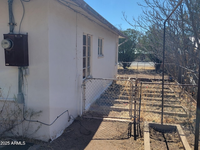 view of property exterior featuring a gate, stucco siding, and fence
