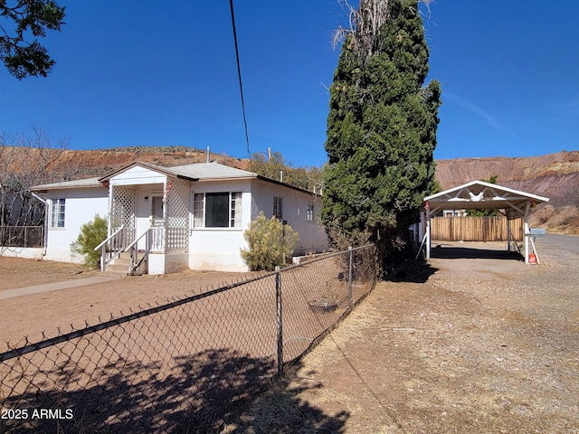 view of front of home featuring a detached carport, dirt driveway, and fence