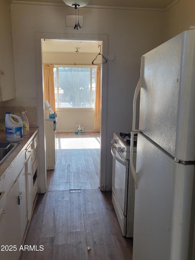 kitchen featuring light wood-type flooring, white appliances, white cabinets, and light countertops