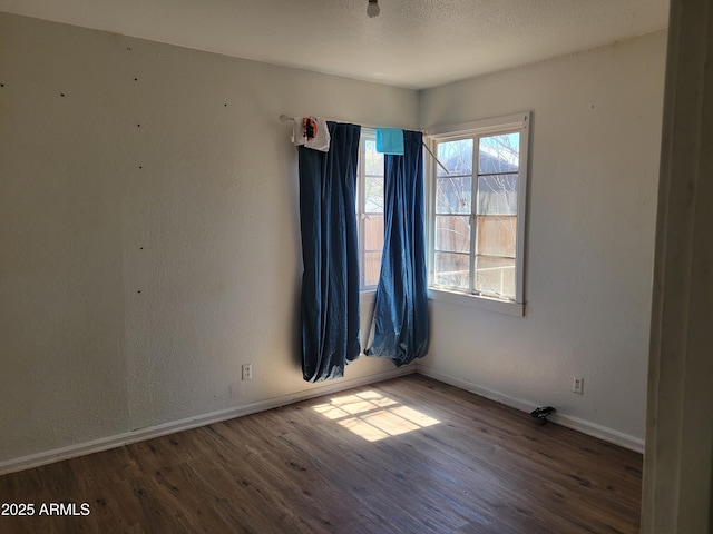 empty room with wood finished floors, baseboards, a textured wall, and a textured ceiling