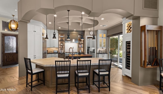 kitchen with decorative light fixtures, a spacious island, sink, and light parquet floors