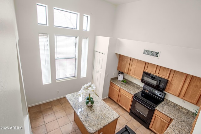 kitchen featuring baseboards, visible vents, a high ceiling, black appliances, and a center island