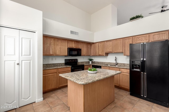 kitchen with visible vents, a kitchen island, black appliances, a ceiling fan, and a sink