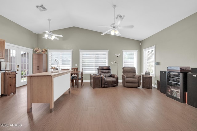 living area featuring a wealth of natural light, ceiling fan, wood finished floors, and visible vents