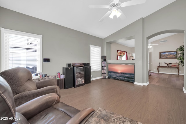 living room featuring ceiling fan, visible vents, arched walkways, wood finished floors, and baseboards