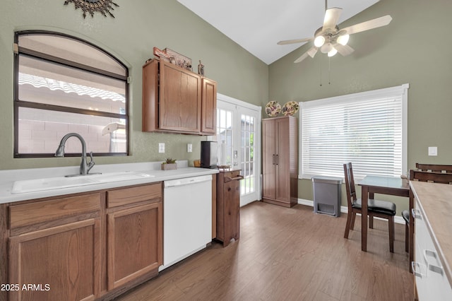 kitchen featuring a ceiling fan, light wood-type flooring, a sink, dishwasher, and vaulted ceiling