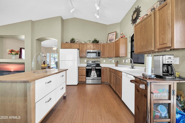 kitchen with a sink, wood finished floors, brown cabinets, rail lighting, and stainless steel appliances
