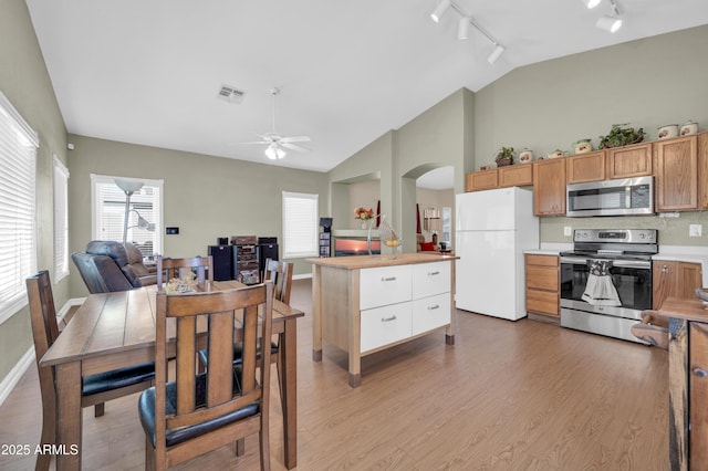 dining room featuring visible vents, rail lighting, light wood-style flooring, and arched walkways