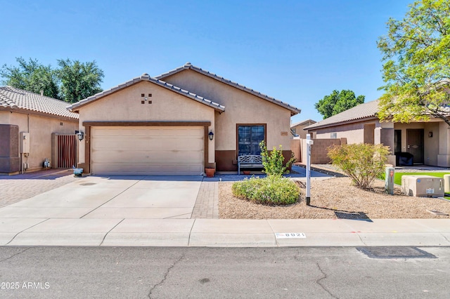 ranch-style house featuring fence, an attached garage, a tile roof, stucco siding, and driveway