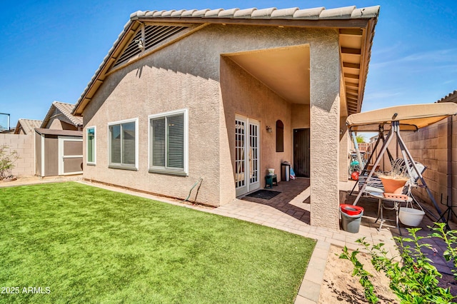 back of property with fence, stucco siding, a shed, french doors, and a patio