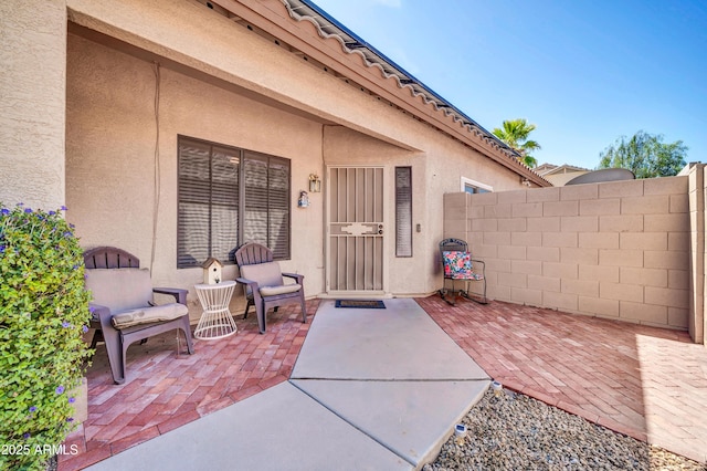 entrance to property with a patio area, stucco siding, and fence