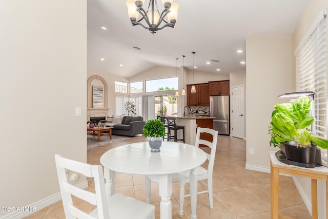 dining area with light tile patterned floors, a notable chandelier, baseboards, and vaulted ceiling