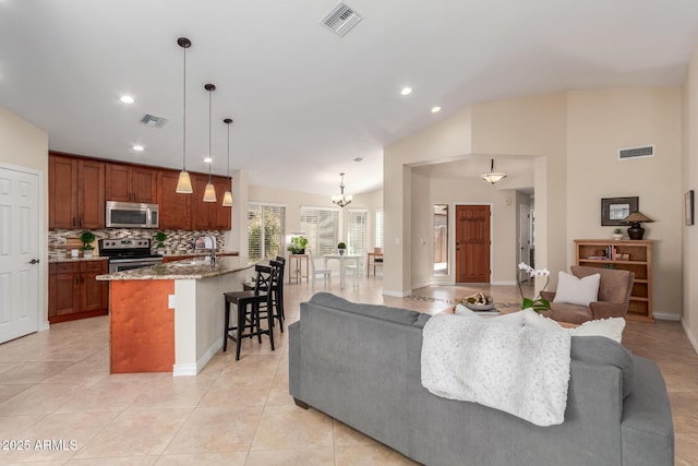 living area featuring vaulted ceiling, light tile patterned floors, and visible vents