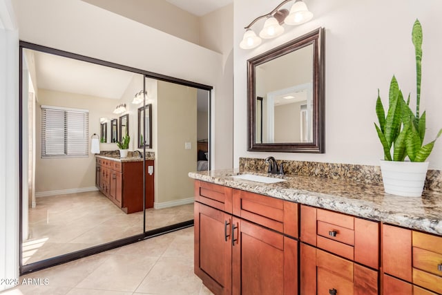 full bath featuring tile patterned floors, two vanities, baseboards, and a sink