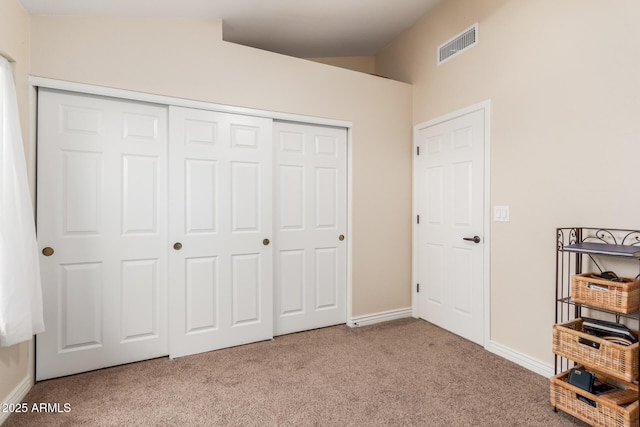 unfurnished bedroom featuring visible vents, baseboards, lofted ceiling, carpet floors, and a closet