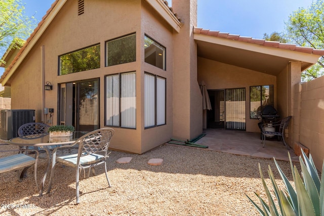 back of property featuring fence, central air condition unit, stucco siding, a chimney, and a patio area