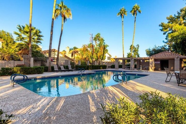 pool with a patio area and fence