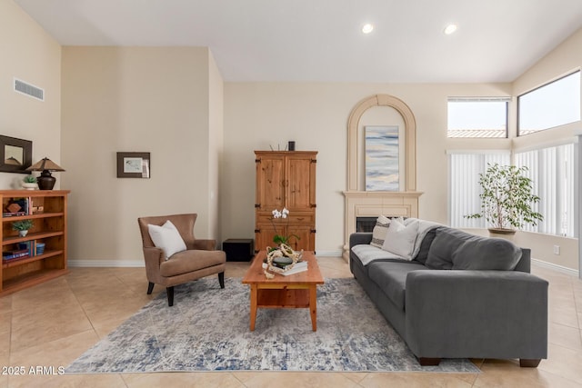 living room featuring a fireplace, light tile patterned flooring, a healthy amount of sunlight, and visible vents