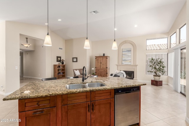 kitchen with light tile patterned floors, light stone countertops, a sink, dishwasher, and open floor plan