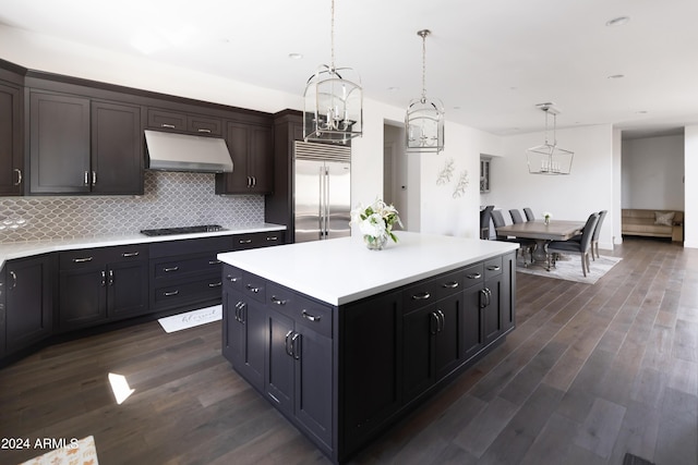 kitchen with backsplash, decorative light fixtures, stainless steel built in fridge, a center island, and dark hardwood / wood-style floors