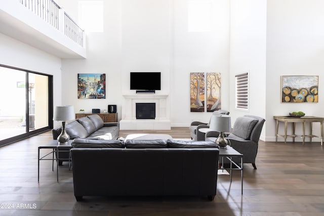 living room with dark hardwood / wood-style floors, a high ceiling, and a tiled fireplace