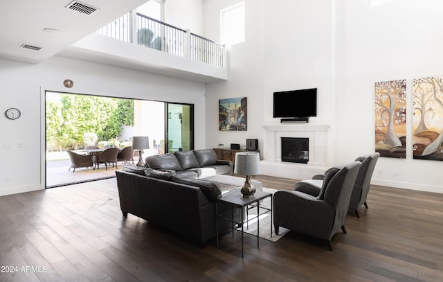 living room featuring dark hardwood / wood-style floors, a towering ceiling, and a fireplace