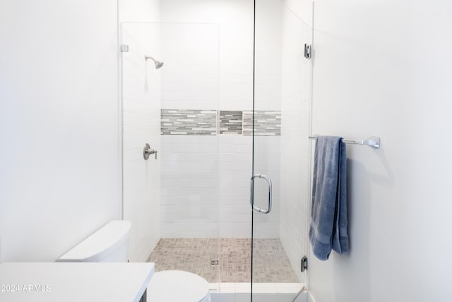 bathroom featuring toilet and a shower with shower door