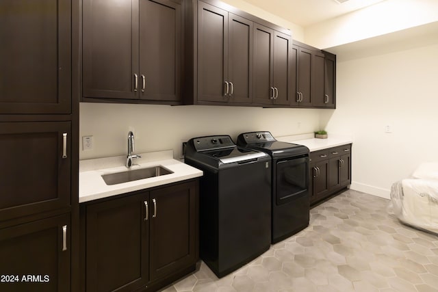 clothes washing area featuring cabinets, sink, and washing machine and dryer