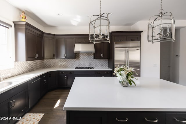 kitchen featuring a chandelier, stainless steel built in fridge, a center island, and exhaust hood