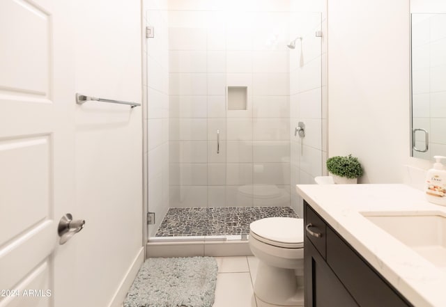 bathroom featuring tile patterned floors, a shower with door, vanity, and toilet