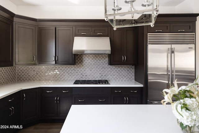 kitchen featuring dark brown cabinetry, gas stovetop, built in fridge, ventilation hood, and backsplash