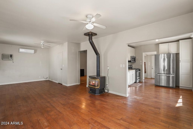 unfurnished living room with a wood stove, ceiling fan, a wall mounted AC, and dark hardwood / wood-style floors