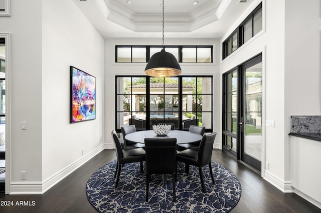 dining space featuring dark wood-type flooring, french doors, crown molding, a towering ceiling, and a tray ceiling