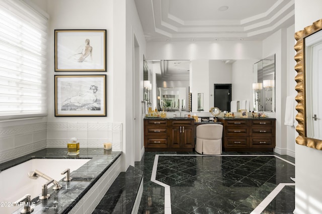 bathroom with a tray ceiling, a bathing tub, vanity, and ornamental molding