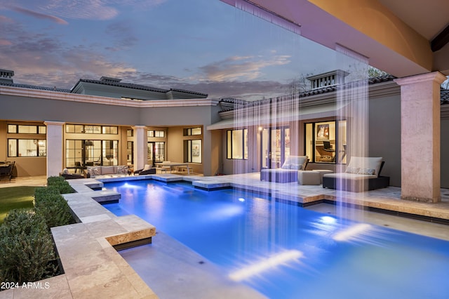 pool at dusk featuring outdoor lounge area and a patio area