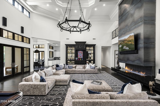 living room with french doors, a towering ceiling, coffered ceiling, a large fireplace, and crown molding