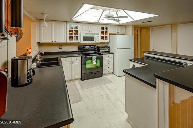 kitchen with sink, white appliances, white cabinets, and a skylight