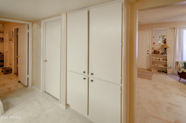 hall with a textured ceiling and light carpet