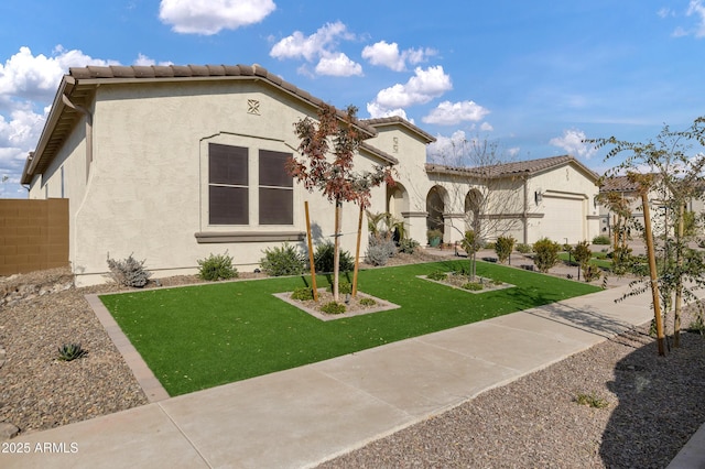 mediterranean / spanish house with a garage and a front lawn