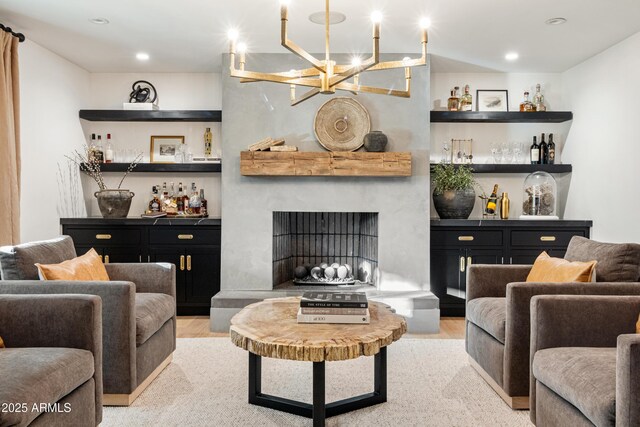 living room with a fireplace, light hardwood / wood-style flooring, and indoor bar