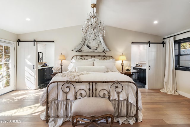 bedroom with lofted ceiling, access to outside, a barn door, ensuite bath, and light hardwood / wood-style flooring