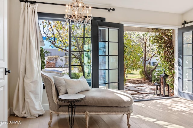 sitting room featuring an inviting chandelier, a barn door, and hardwood / wood-style floors