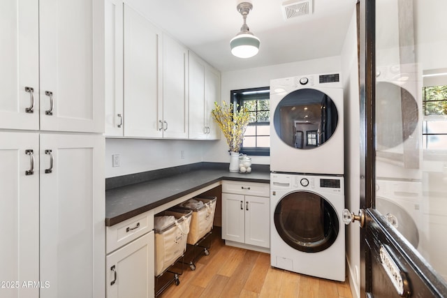 clothes washing area featuring stacked washing maching and dryer and light hardwood / wood-style floors