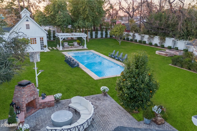 view of pool with an outdoor brick fireplace, a yard, a pergola, a patio, and an outbuilding