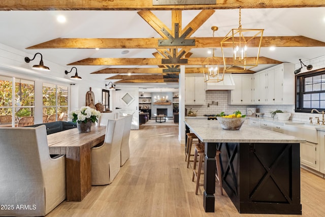 kitchen with decorative light fixtures, sink, white cabinets, and a spacious island